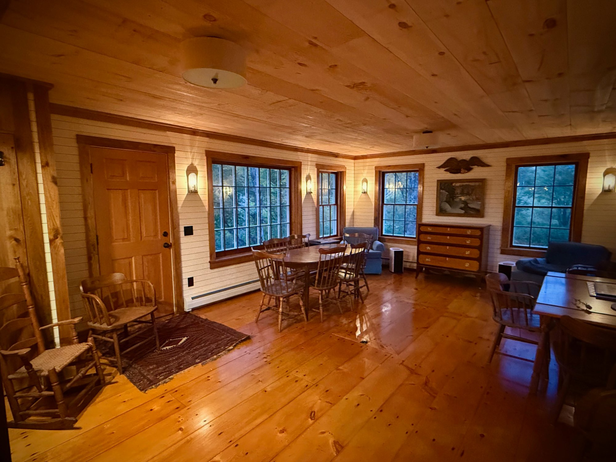 Interior of the restored 1810s village farmhouse — warm pine floors, antique furnishings, and colonial windows at MacIsaac Highland